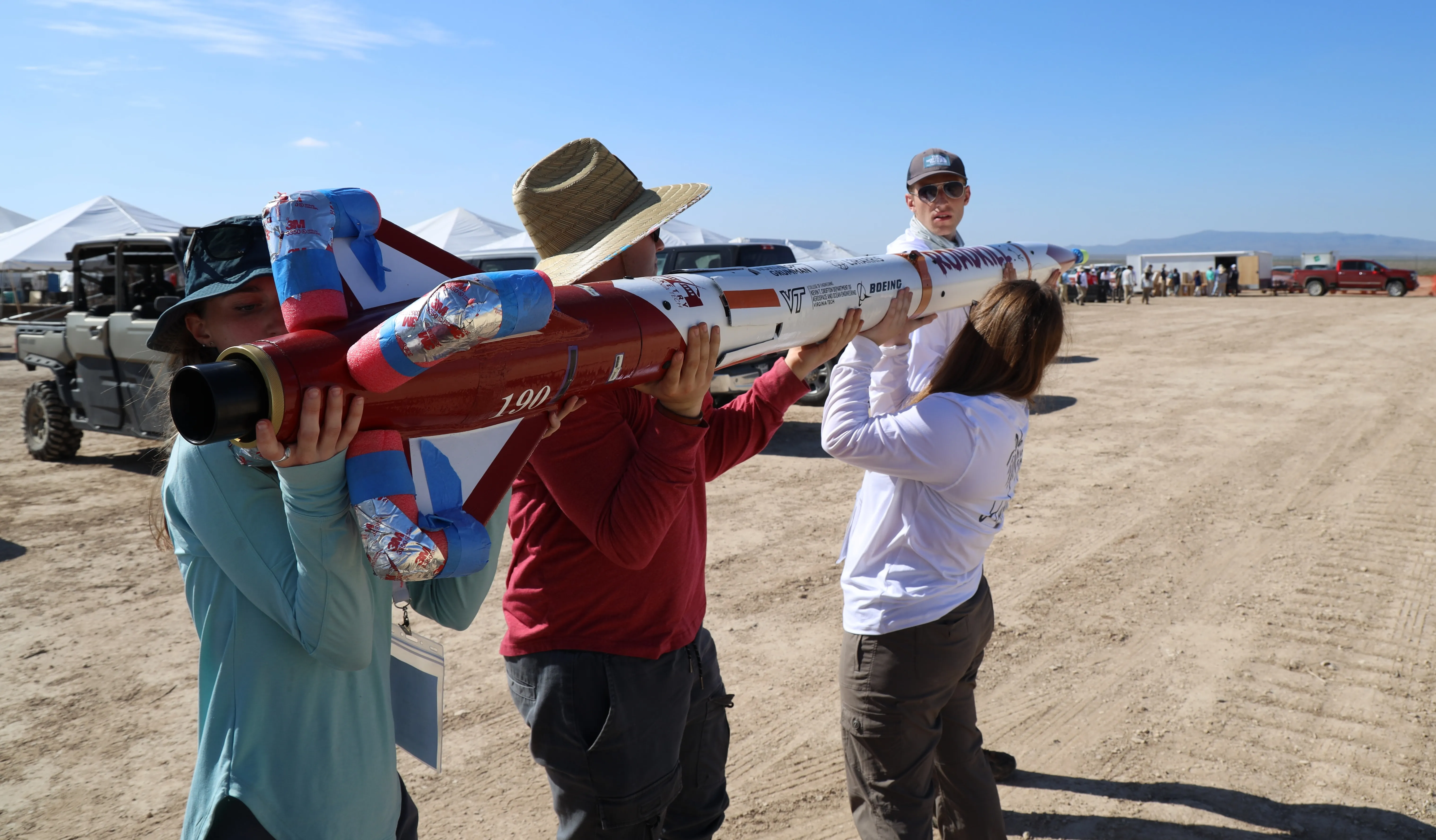 Several Members of the Rocketry at Virginia Tech team standing in front of the teams rocket at the Spaceport America Cup loading onto the launch rail